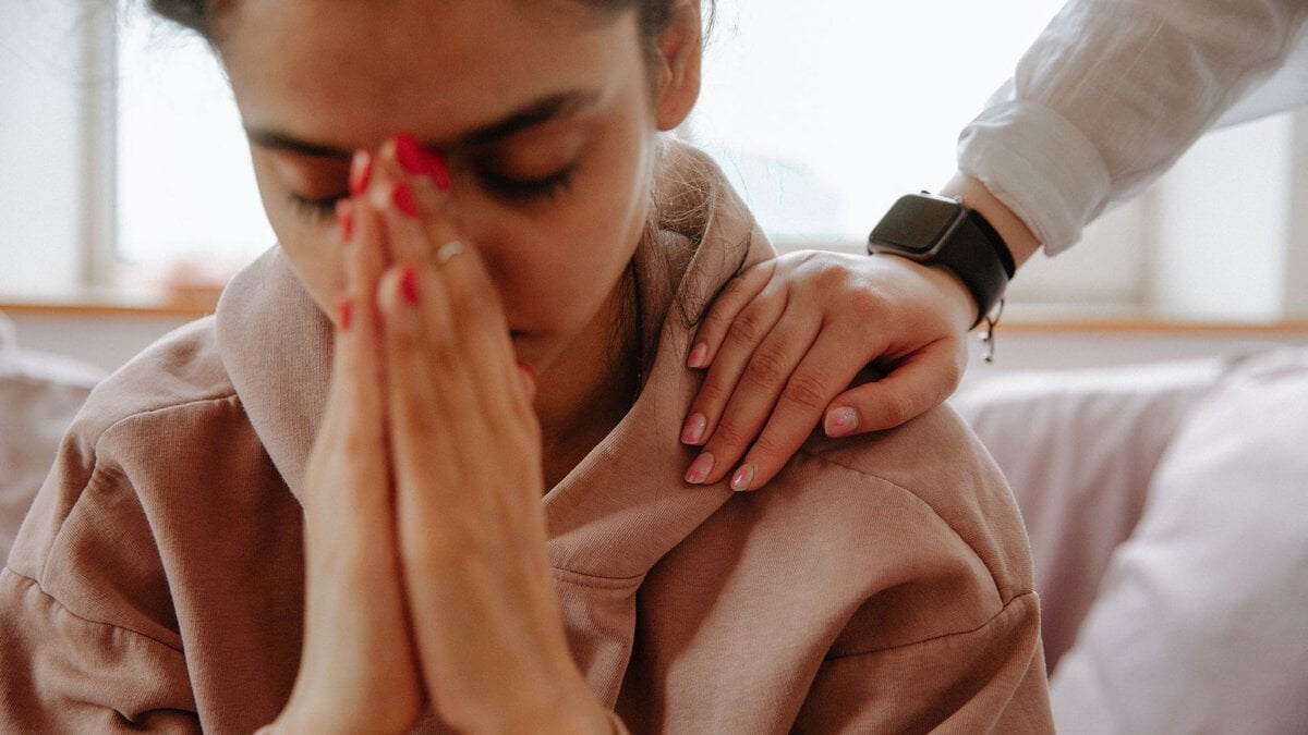 A comforting hand on a woman’s shoulder