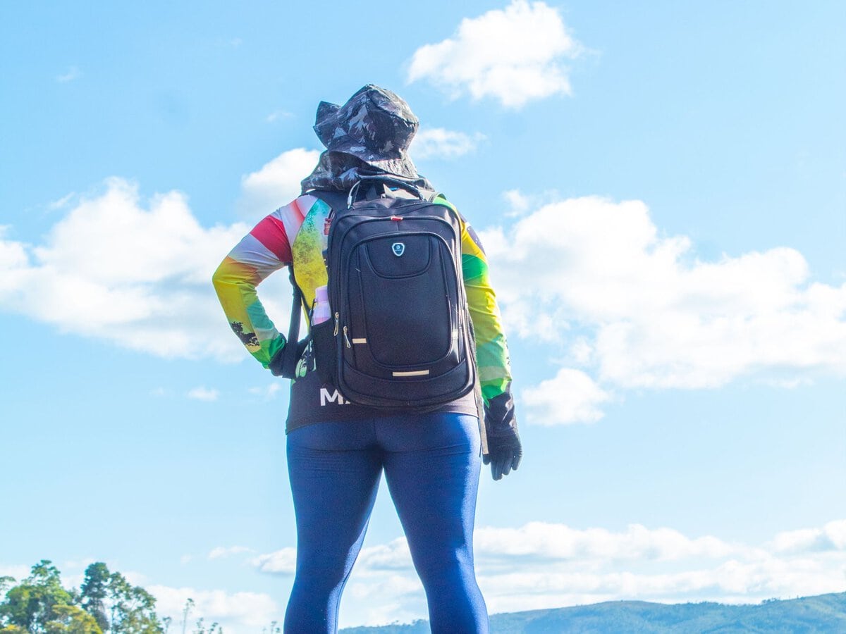 A hiker with a backpack looking across a mountain landscape