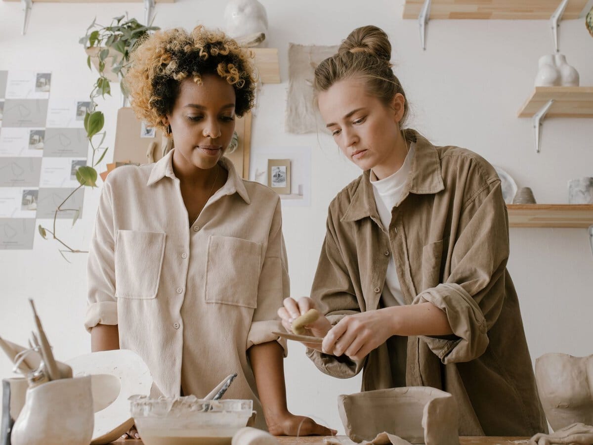 Two women practicing pottery together in a studio