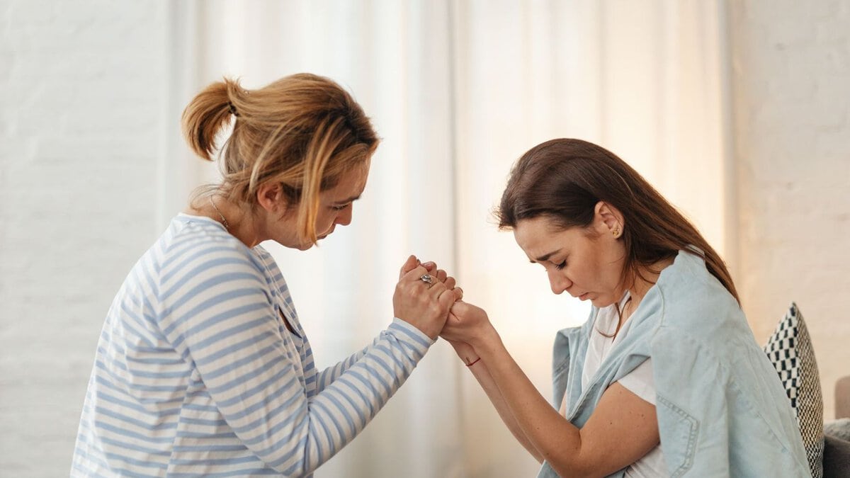 Two women holding hands during a supportive conversation
