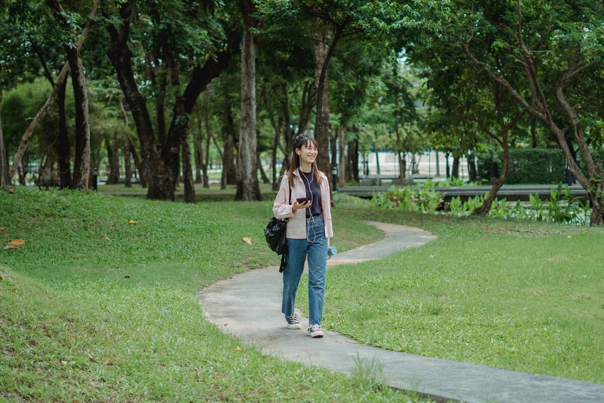 Woman taking a walk along a green park path