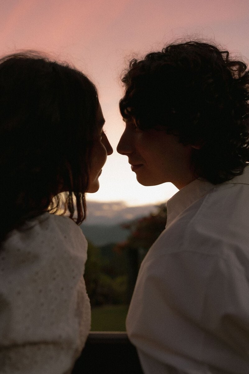 Couple facing each other against an evening sky
