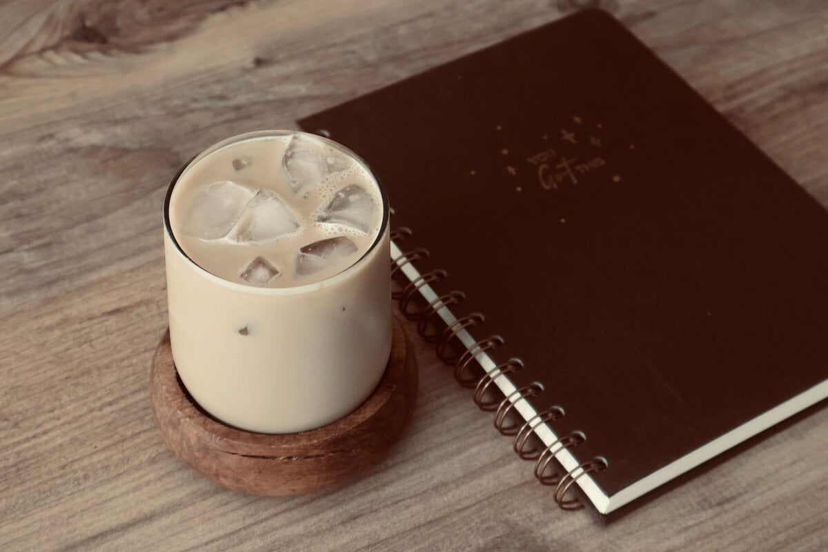 Iced coffee beside a notebook and pen