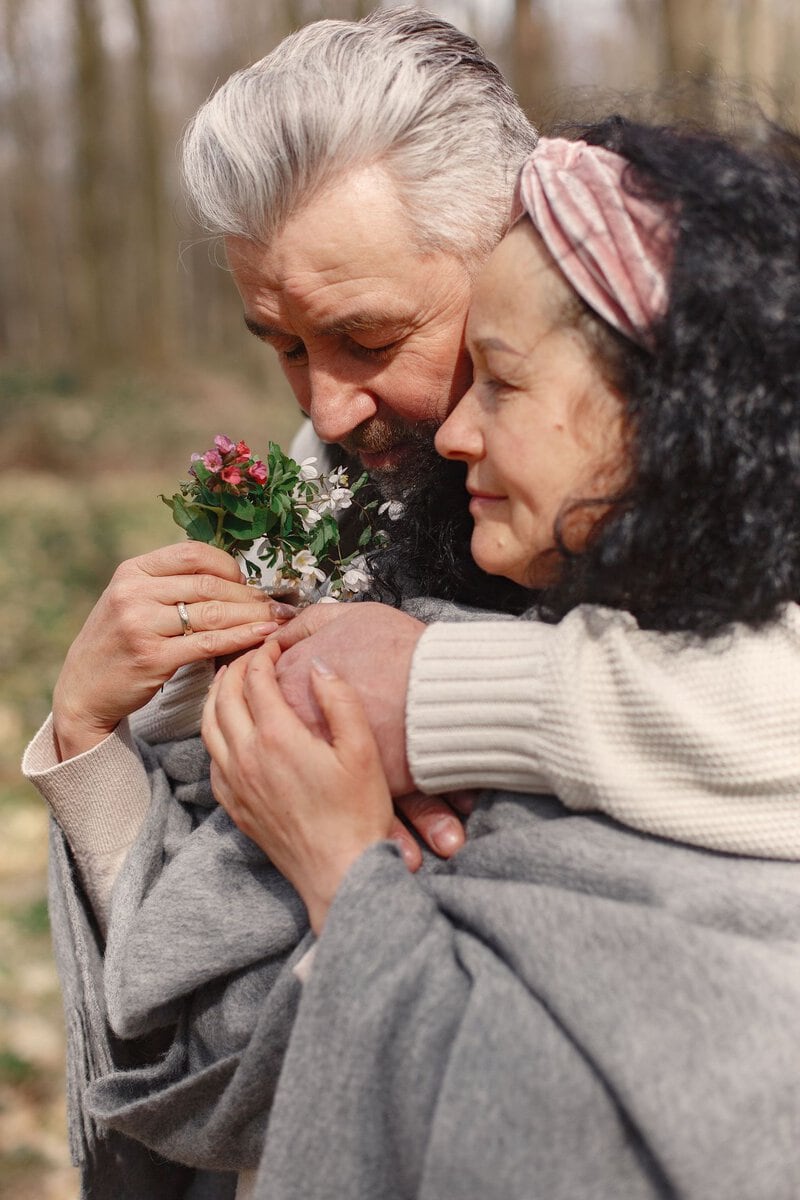 Older couple holding flowers and embracing