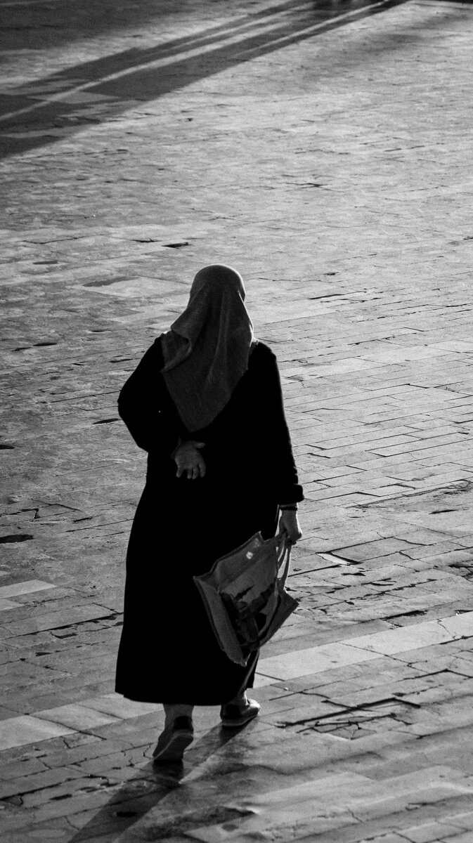 A woman walking along a cobbled street