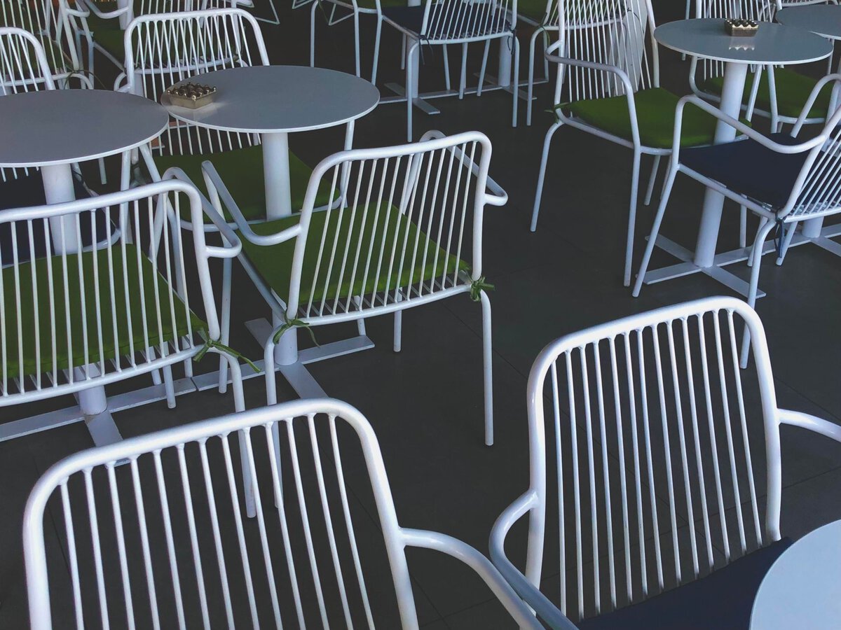 White cafe chairs with green cushions