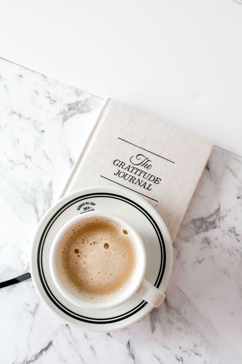 Coffee cup resting on a gratitude journal