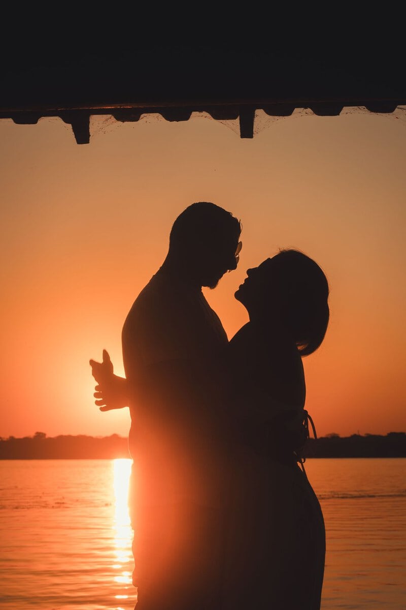 Silhouettes of a couple by the water at sunset