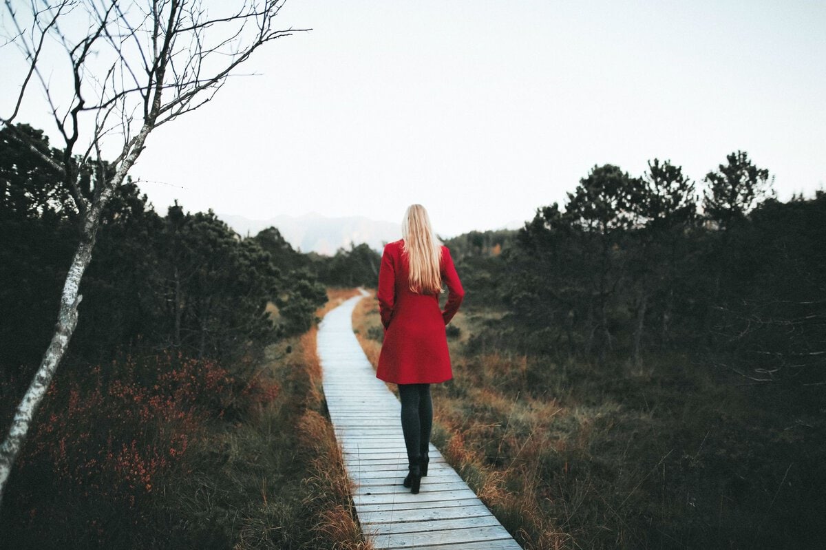 Woman in a red coat walking along a boardwalk