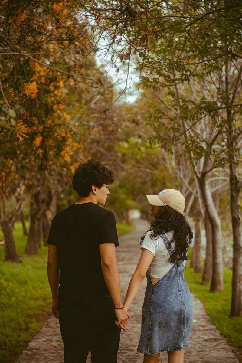 Couple holding hands on a tree-lined path