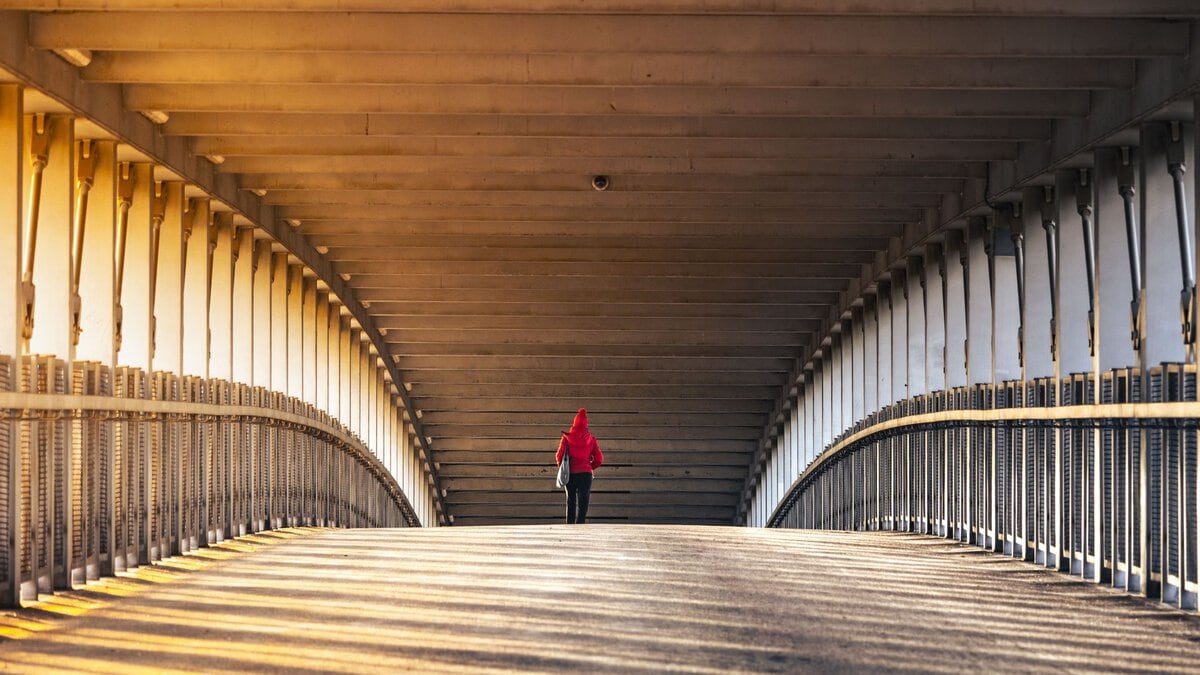 A pedestrian crossing a wide wooden bridge