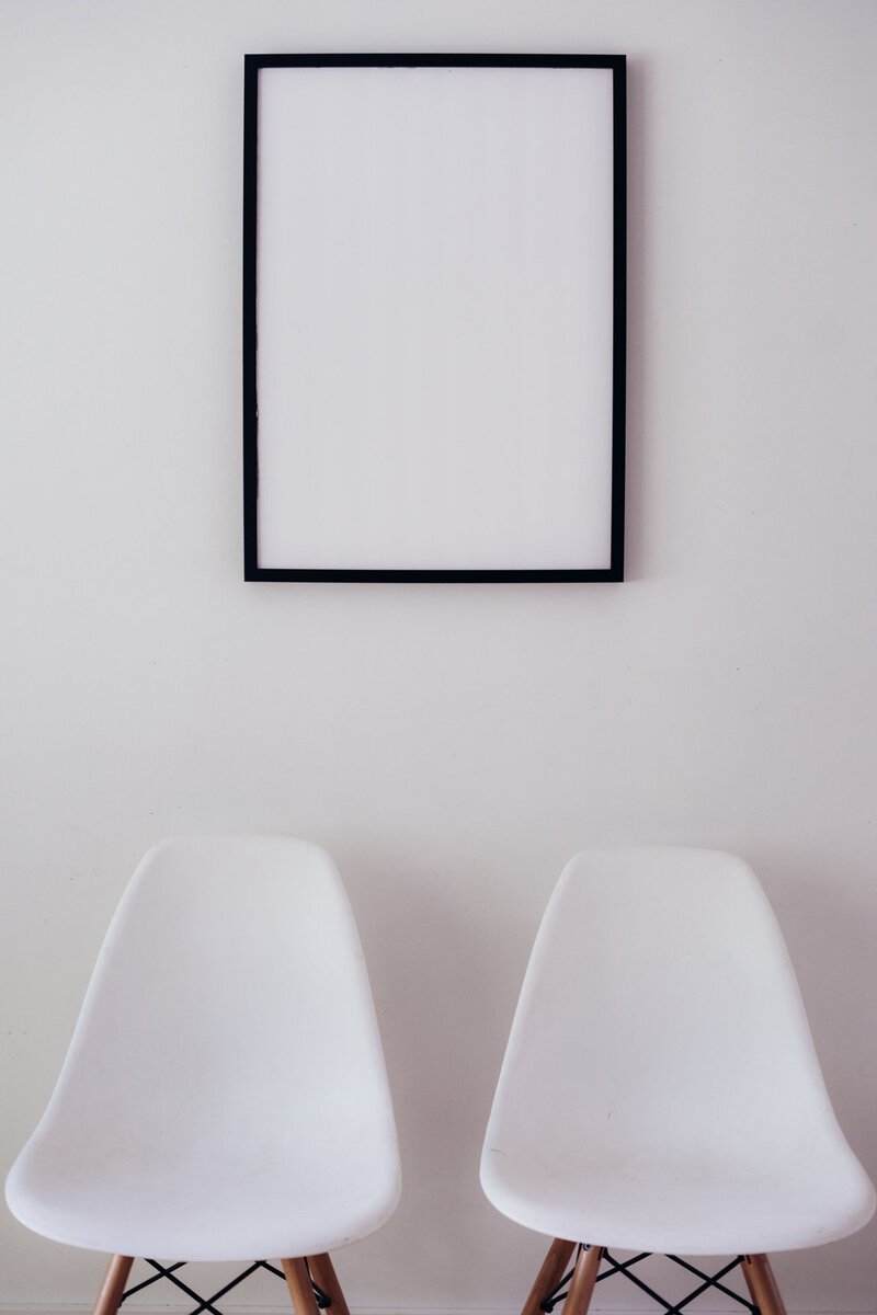 Two white chairs beneath an empty frame
