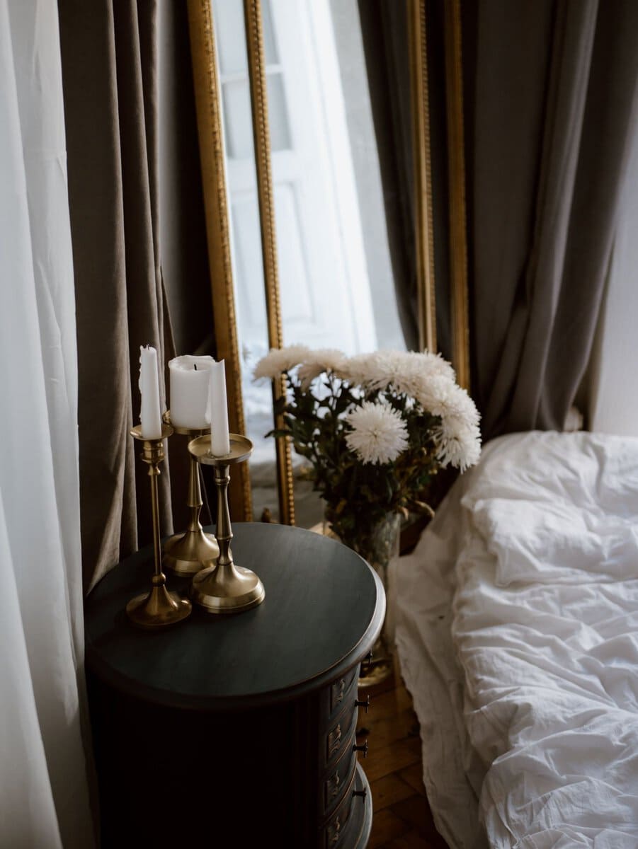 Candles and flowers beside a bed