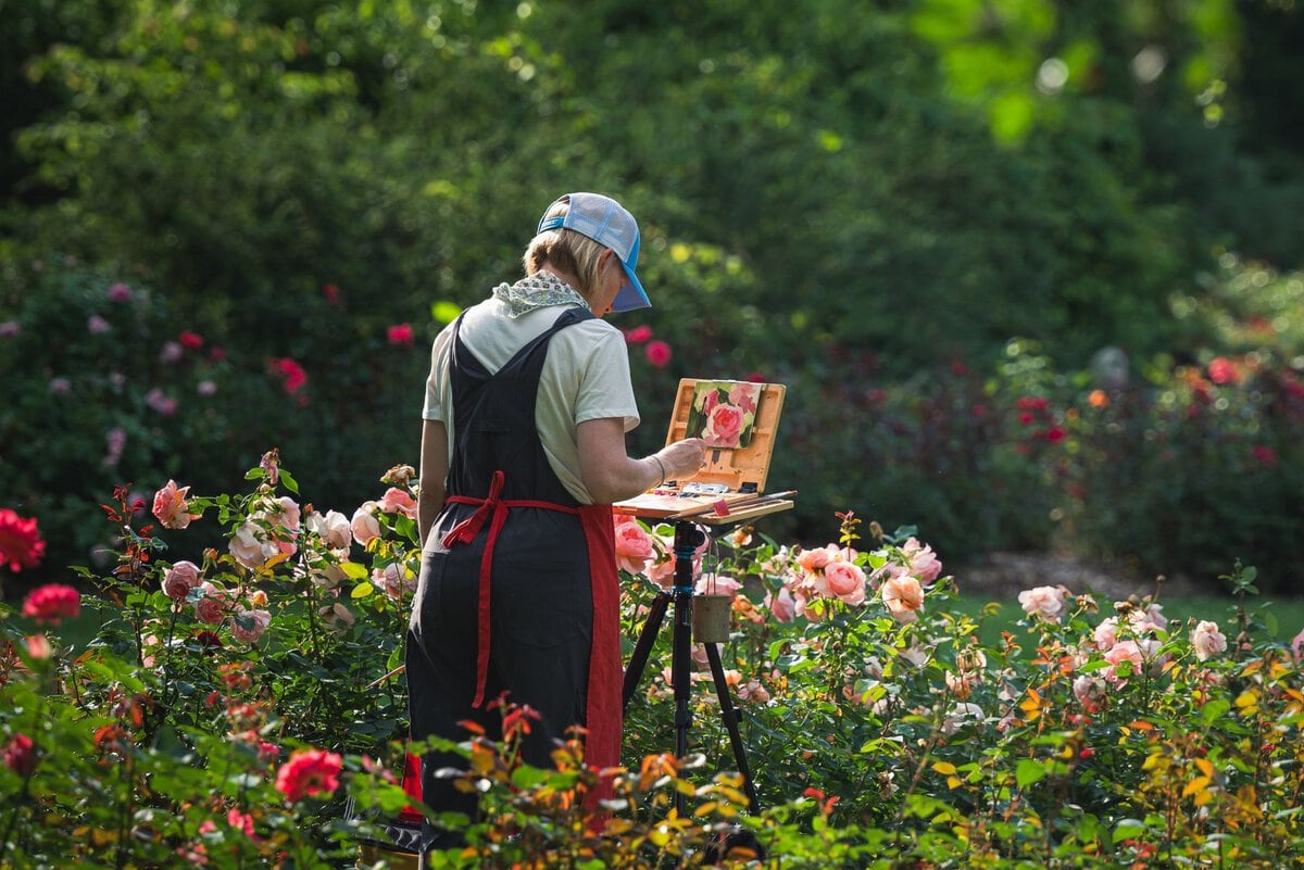Woman painting flowers in a garden