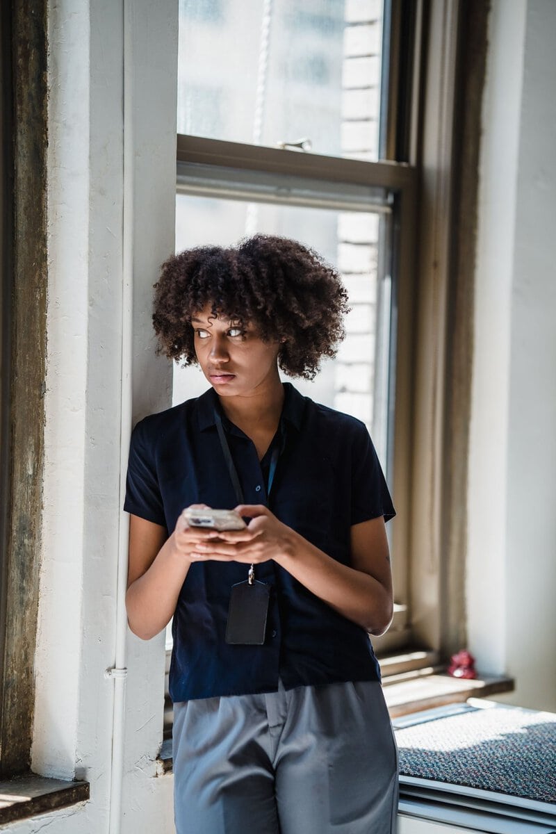 Woman holding a phone beside a window